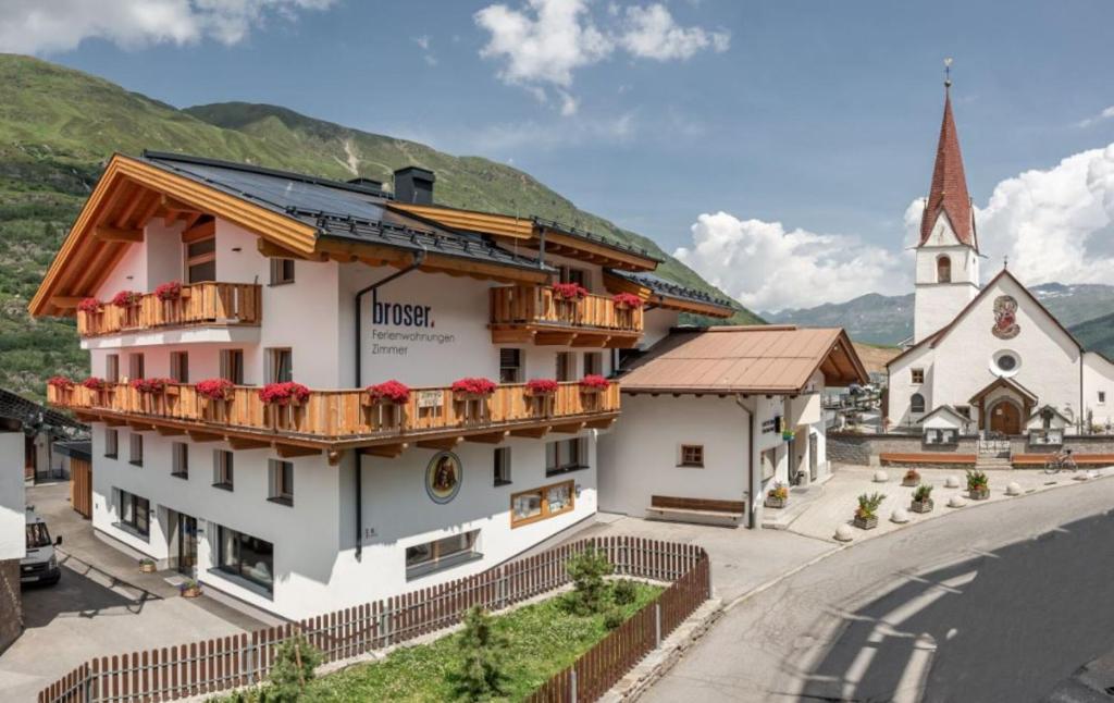 a building with flowers on the balconies and a church at Frühstückspension Broser in Obergurgl