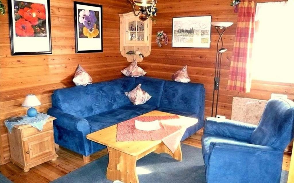 uma sala de estar com um sofá azul e uma mesa em Ferienhaus Nr 5, Typ A, Feriendorf Jägerpark, Bayerischer Wald em Viechtach