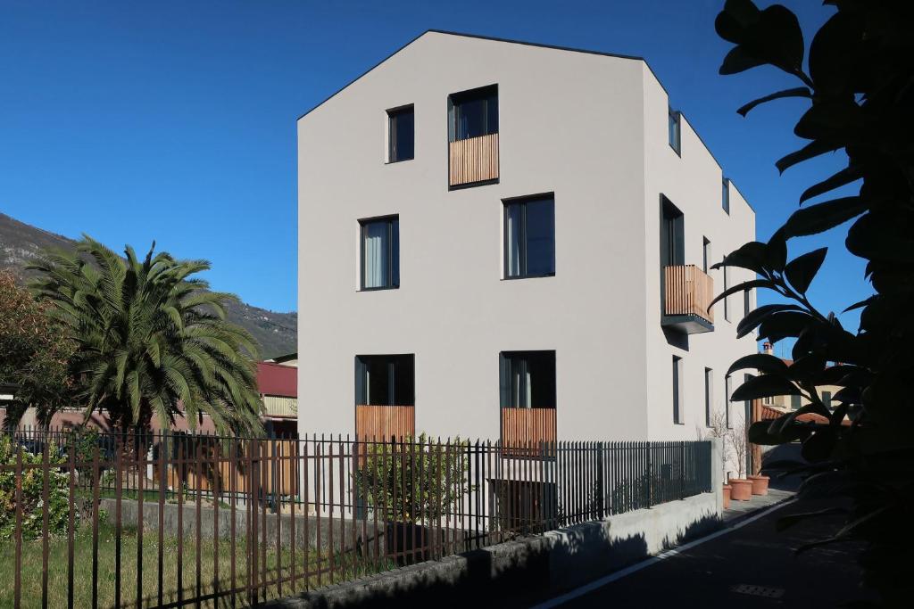 a white building with a fence in front of it at Picobello Lago in Mandello del Lario