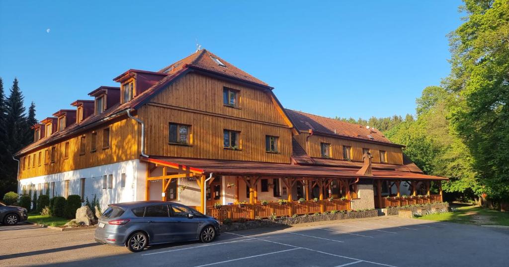 Radešín的住宿－Balónový hotel a pivovar Radešín，停放在大型木质建筑前的汽车