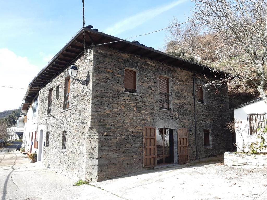 an old stone building with wooden doors on a street at Casa Rural Estrella del Sil in Corbón del Sil