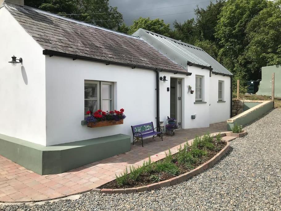 a white cottage with a bench in front of it at An Bothán-Cosy Cottage in the Cooley Mountains in Dundalk