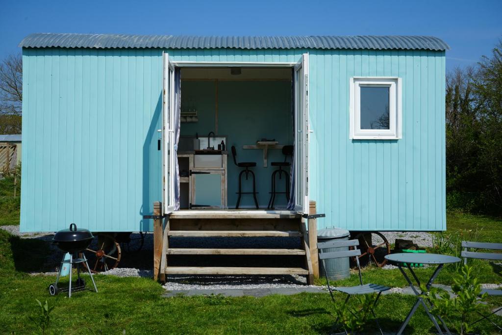 un cobertizo azul con una escalera que conduce a la puerta en BlueBell, en Tenby