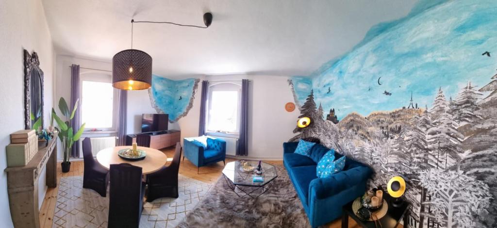 una sala de estar con un sofá azul y una pintura en la pared en Harztour 3 Ferienwohnung, en Quedlinburg