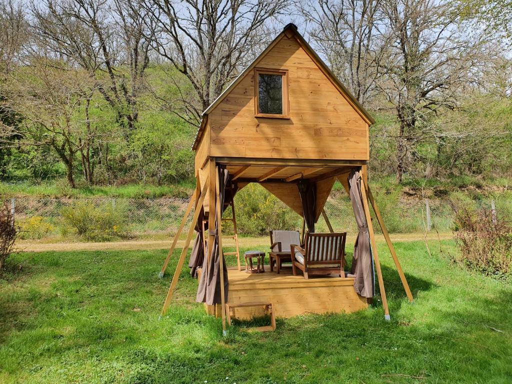 a wooden gazebo with a table and a chair in the grass at L'alternatif in Huriel