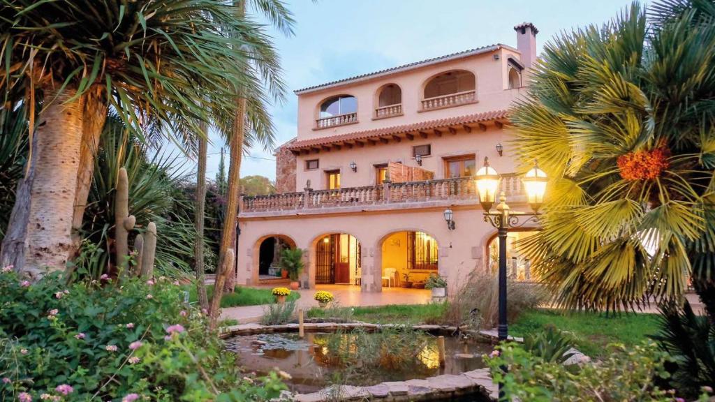 a large house with a pond and palm trees at Open Sky Villa in Denia