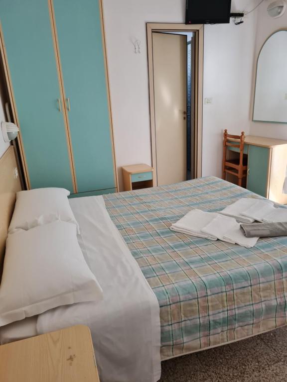 um quarto com uma cama com lençóis brancos e uma mesa em Hotel Marconi Miramare em Rimini