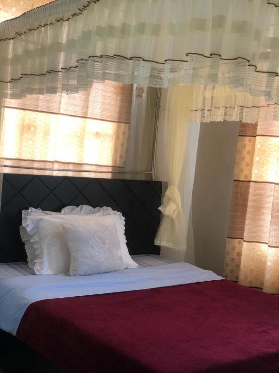 a bedroom with a bed with white pillows and a window at Brooks apartments in Kampala