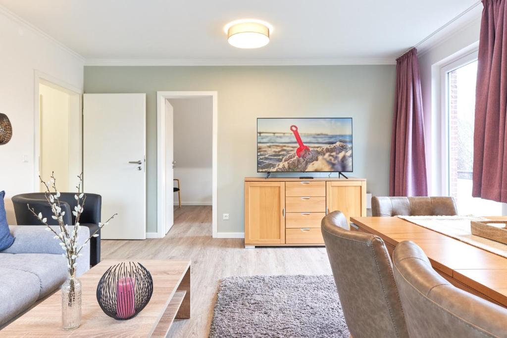 a living room with a table and a red bird on a dresser at SeeZeit Ferienwohnungen in Timmendorfer Strand