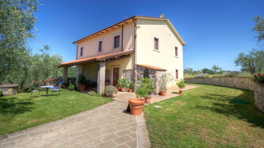una pequeña casa blanca con un patio de césped en Il Poggio Dell'Artilla, en Castiglione in Teverina