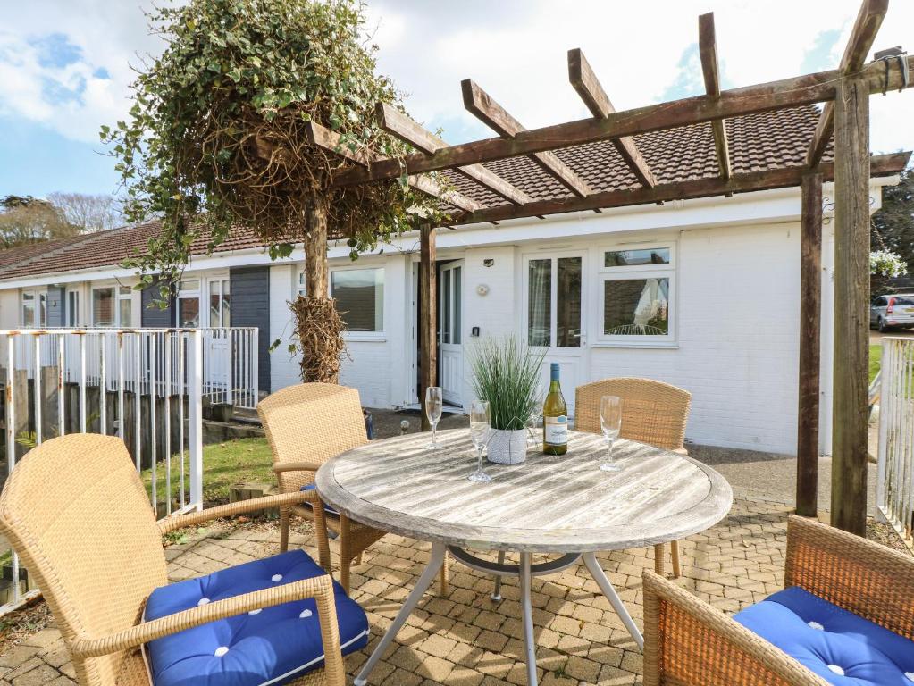 a patio with a table and chairs and a pergola at 8 Munday Cottages in Yarmouth