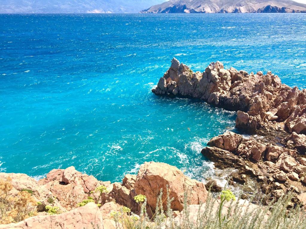 a view of the ocean from a rocky shore at Apartments Ein Haus in der Sonne in Malinska