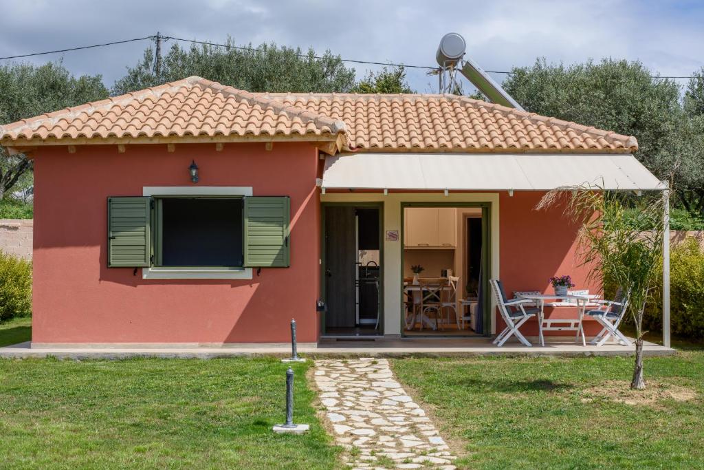 a small red house with a table in front of it at Comfeto & Mandolato Sweet Houses in Lakíthra