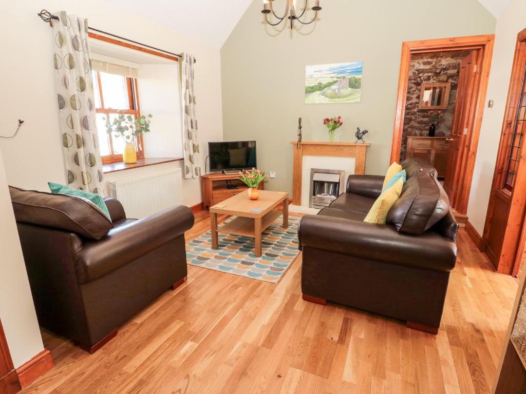a living room with two leather chairs and a fireplace at Cygnet Cottage in Berwick-Upon-Tweed