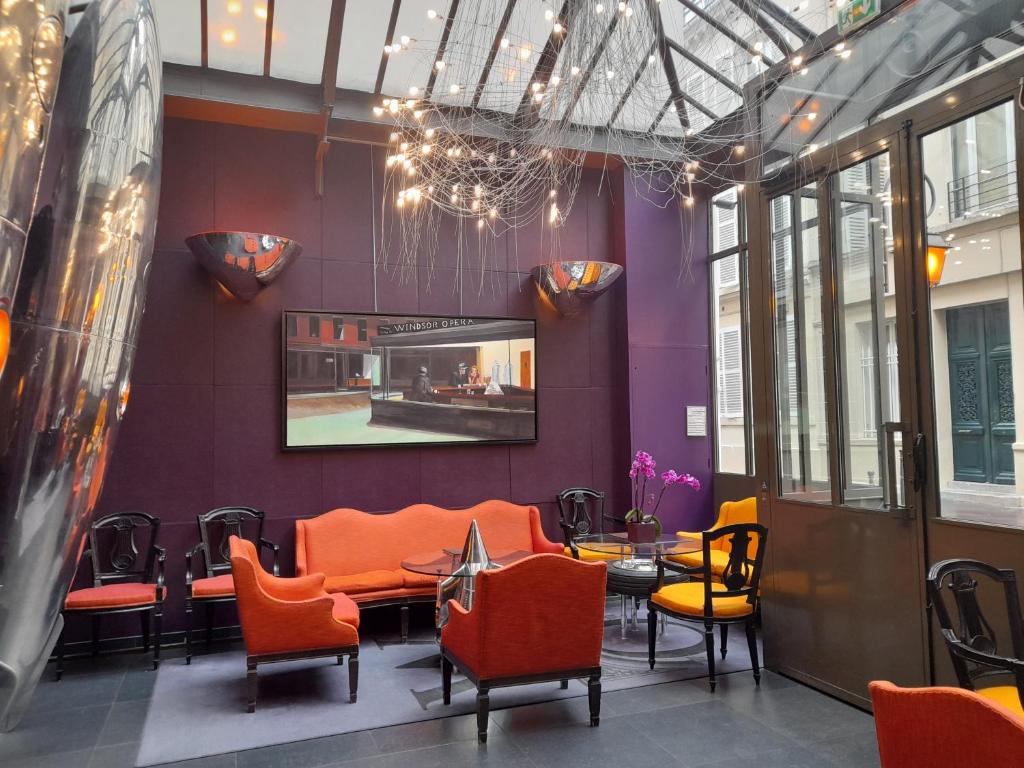 パリにあるウィンザー オペラの建物内のオレンジ色の椅子とテーブルが備わるレストラン