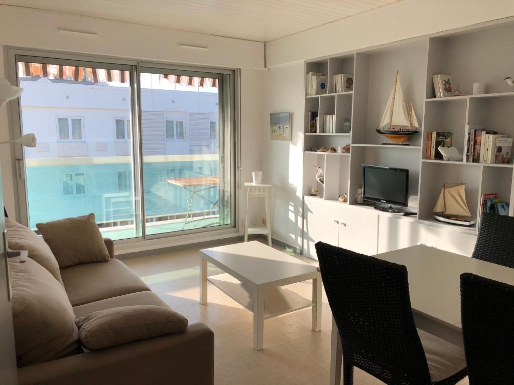 a living room with a couch and a table and a window at JARDIN 308 Appartement avec Terrasse et Parking in Arcachon