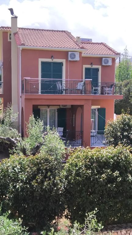 a large pink house with a large balcony at Villa Eleftheria in Karavomylos