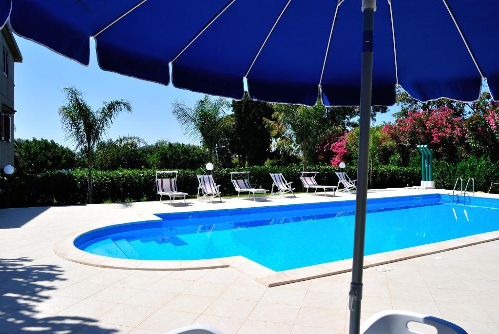 a blue swimming pool with chairs and an umbrella at C'era Una Volta in Ricadi