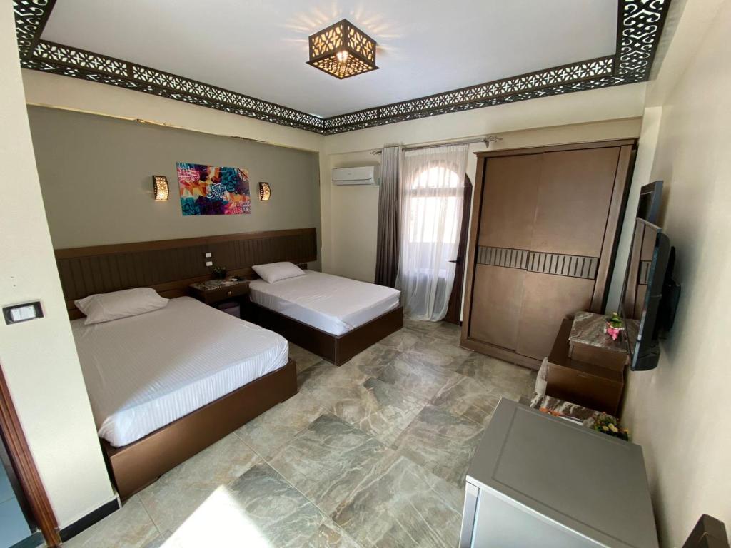 una camera d'albergo con due letti e una televisione di Shabana House a Dahab