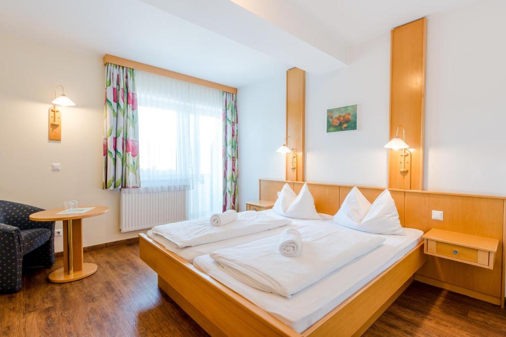 a bedroom with a large bed with white sheets at Hotel & Appartements Erlenheim in Velden am Wörthersee