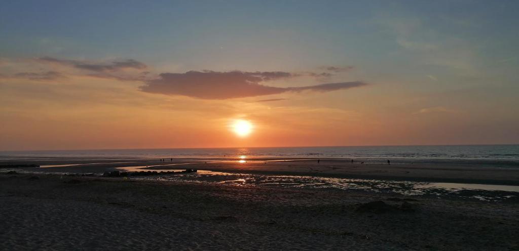 - un coucher de soleil sur la plage avec des personnes se promenant sur la plage dans l'établissement Bel appartement T2 150m plage et tous commerces, à Villers-sur-Mer