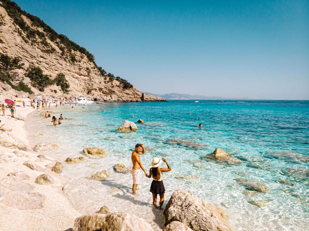 two people standing on a beach near the water at Le Corti Sarde Apartments in Bari Sardo