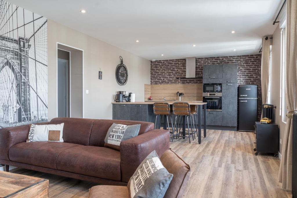 a living room with a couch and a kitchen at voyageurs in Valognes