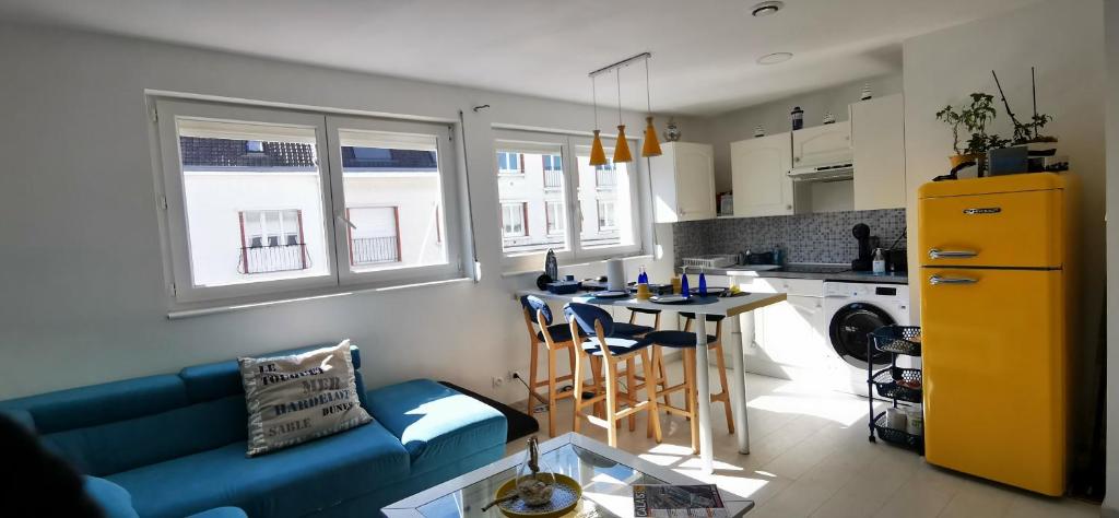 een woonkamer met een blauwe bank en een keuken bij Bulle Marine in Calais