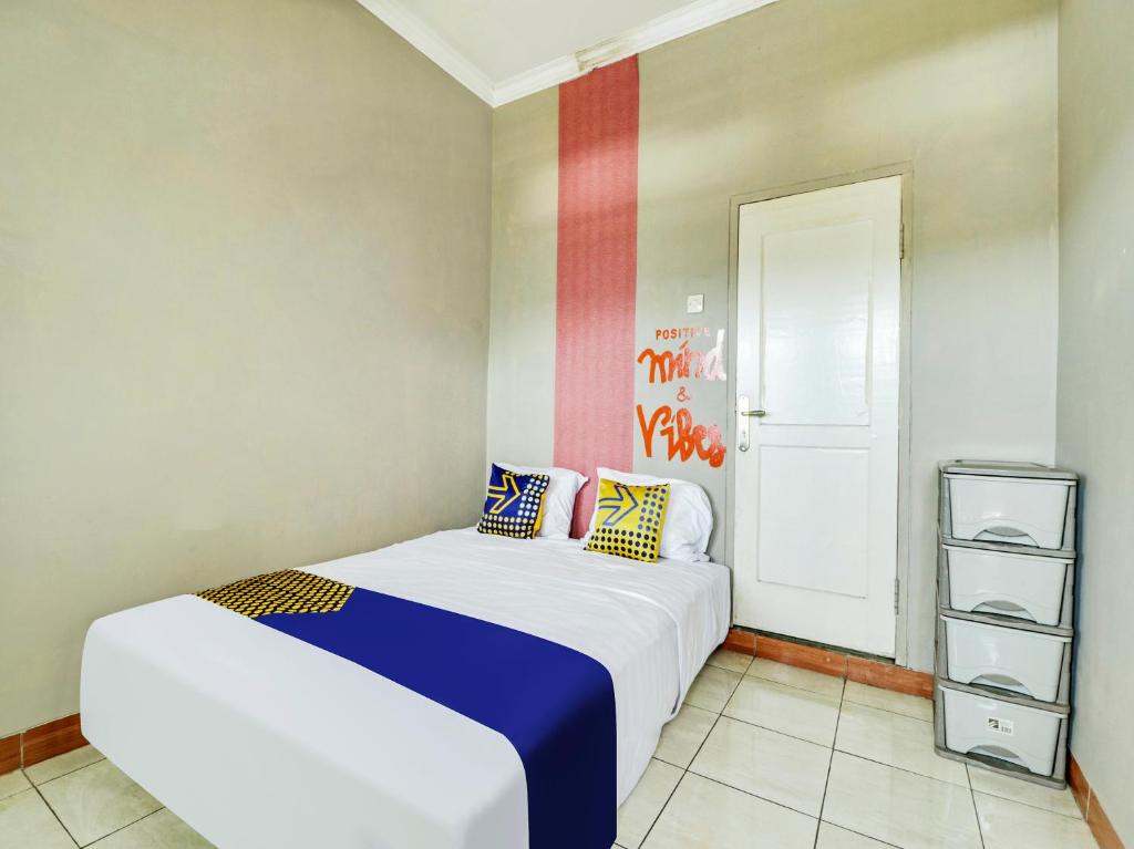 1 dormitorio con 1 cama blanca grande con almohadas coloridas en SPOT ON 91135 Hanami Syariah, en Bandung