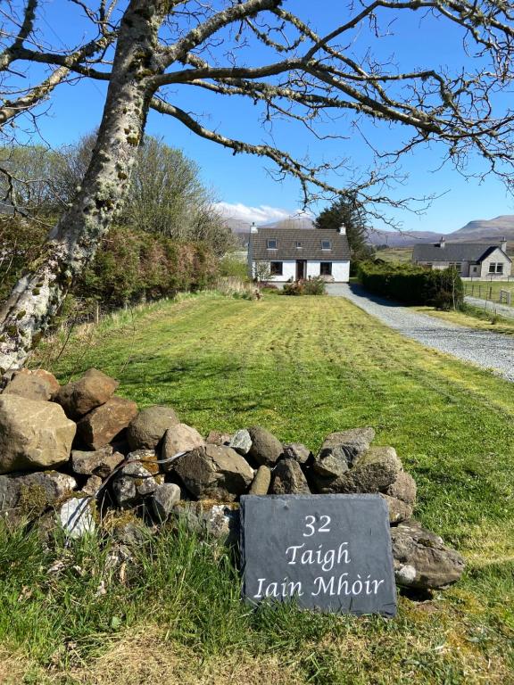 una señal en un montón de rocas delante de una casa en Taigh Iain Mhòir en Skeabost