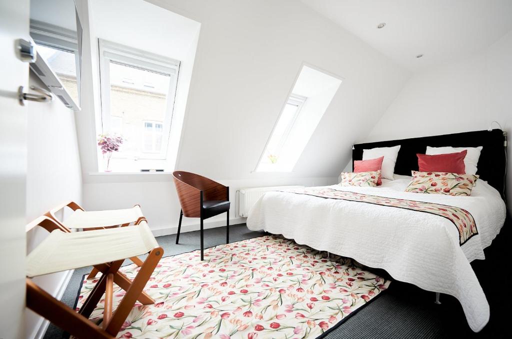 a white bedroom with a bed and a chair at Torvets B&B in Nykøbing Falster