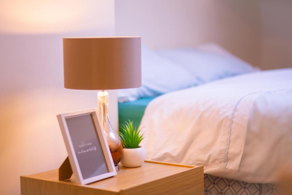 een lamp op een nachtkastje naast een bed bij Anfield Apartment in Liverpool