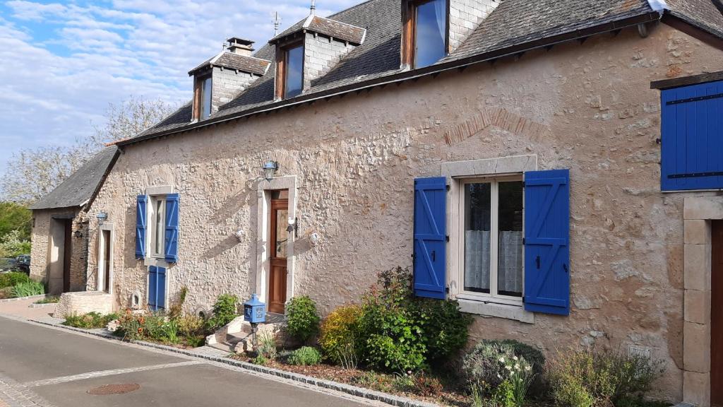une vieille maison en pierre avec volets bleus dans une rue dans l'établissement La Ménagerie, à Maigné