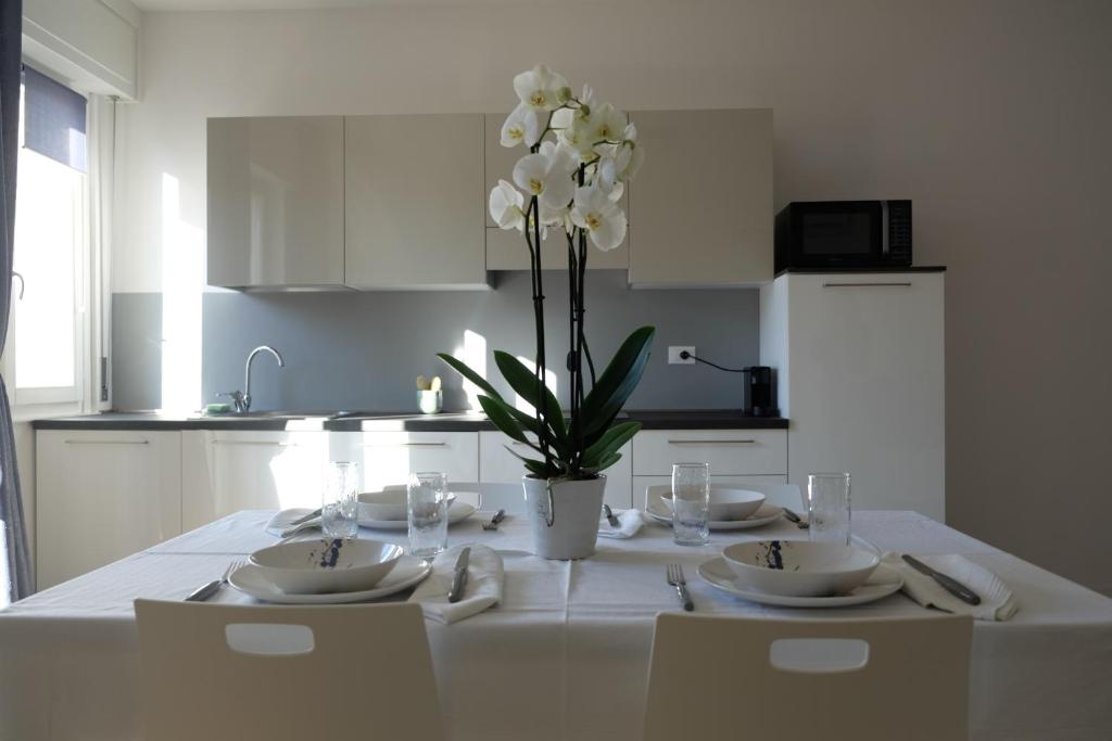 a white kitchen with a table with a vase of flowers at Appartamenti Bellini in Bardolino