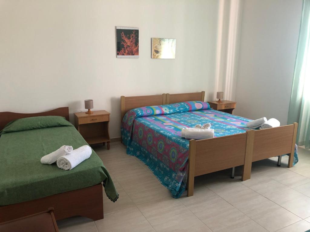1 dormitorio con 2 camas y toallas. en Sirenetta, en Torre Suda