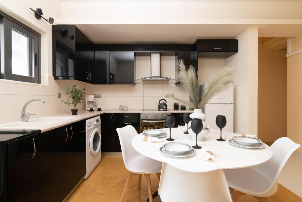 a kitchen with a white table and white chairs at Nostalgia Apartments Zante in Zakynthos