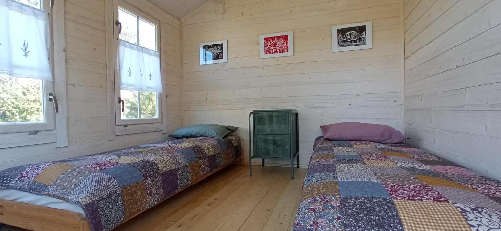 two beds in a room with wooden walls and windows at Domek Na Ustroniu in Sasino