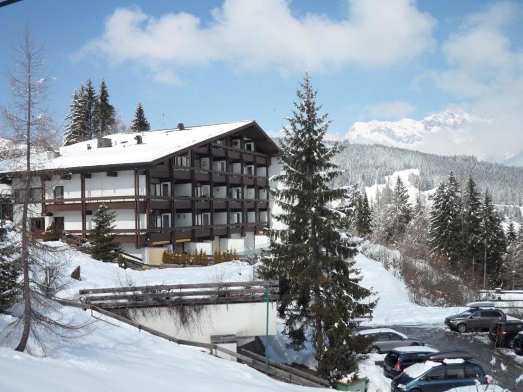 un gran edificio en la nieve con coches aparcados delante en Ferienwohnung Nr 26, Appartementhaus-Hintermoos, Maria-Alm, Österreich, en Bachwinkl