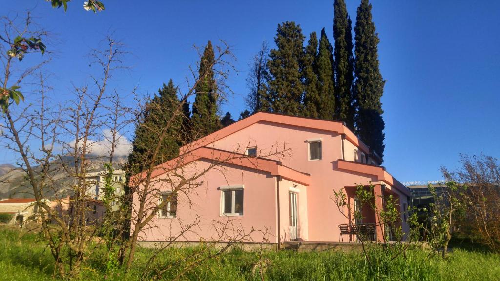 una casa rosa en un campo con árboles en Hostel Hangout en Bar