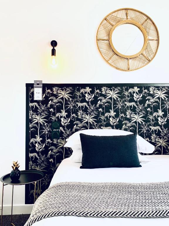 a bedroom with a black and white bed and a mirror at Hôtel Gaspard in Le Touquet-Paris-Plage