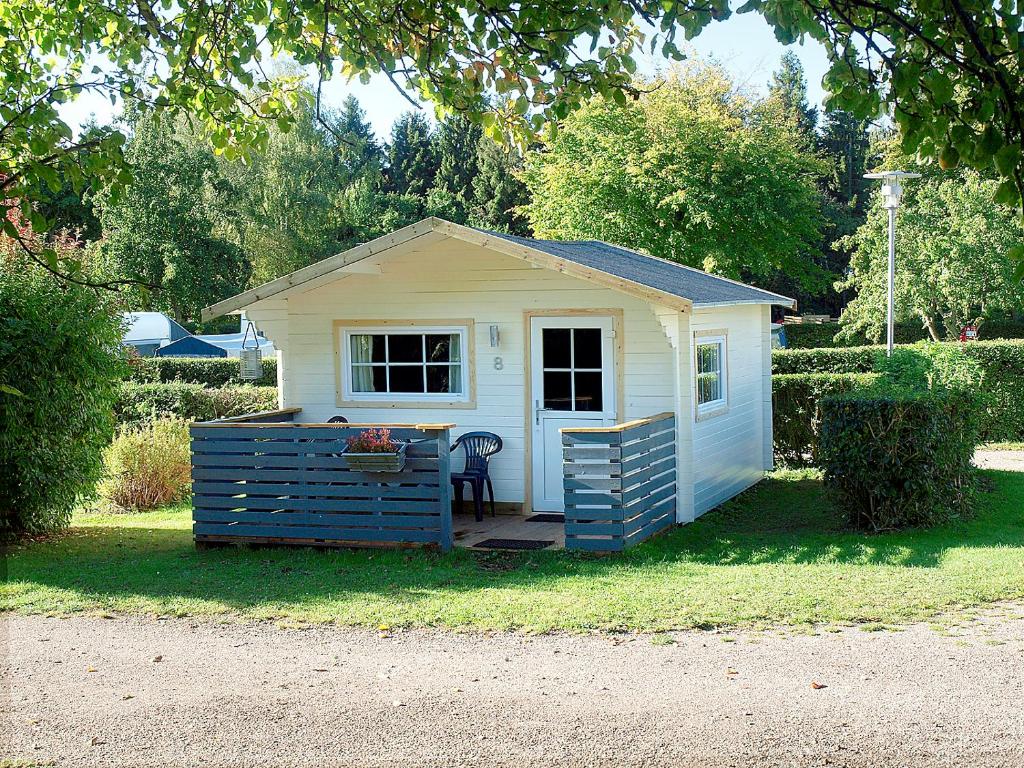 um pequeno galpão branco sentado na relva em Guldborg Camping & Cottages em Guldborg
