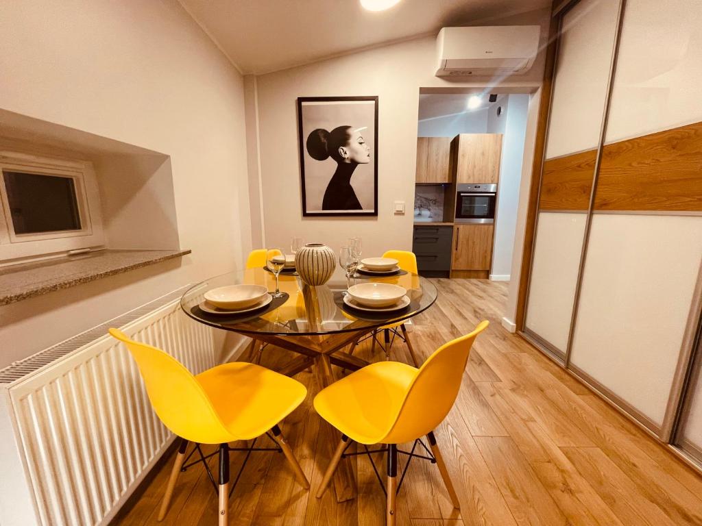 een eetkamer met een tafel en gele stoelen bij Apartamenty KTW Kościuszki 41 - SKY & DESIGN in Katowice