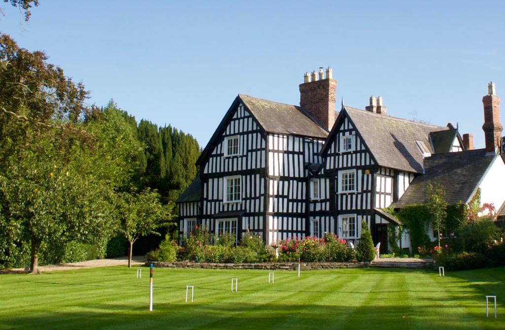 uma grande casa a preto e branco com um relvado verde em Rorrington Hall em Chirbury