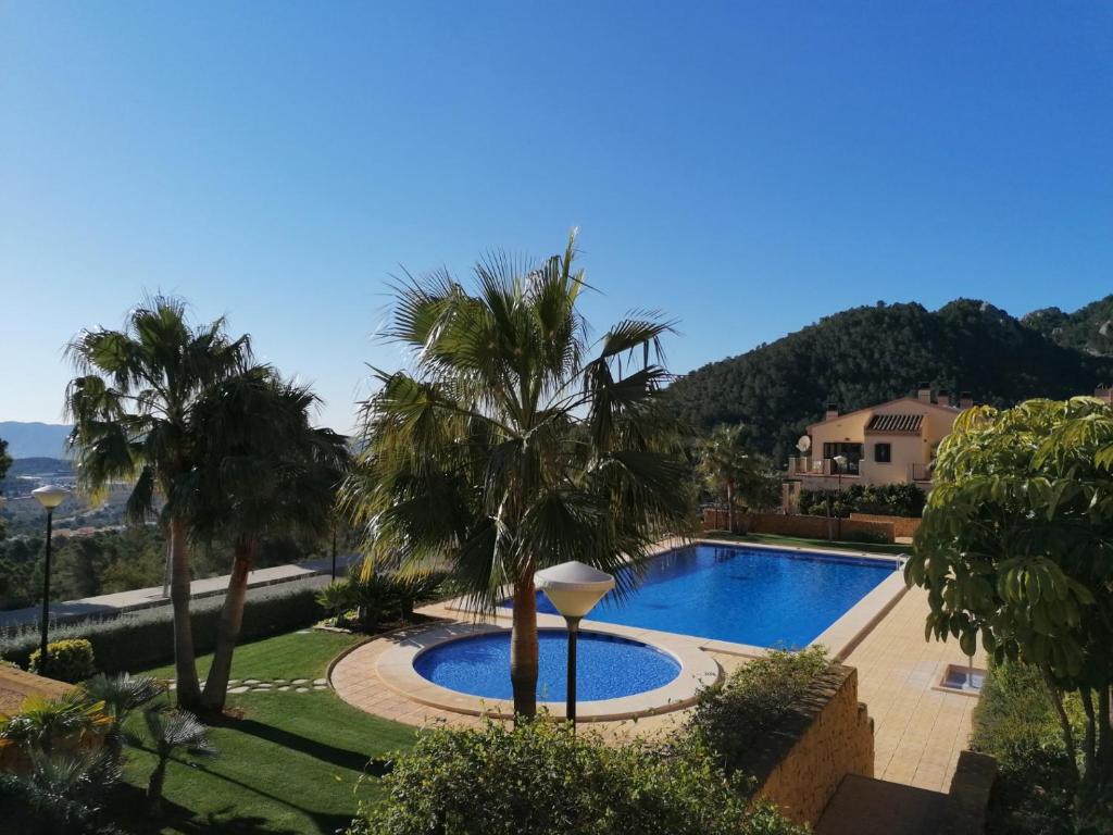 a swimming pool in a yard with palm trees at Cumbre Las Jarras in Polop