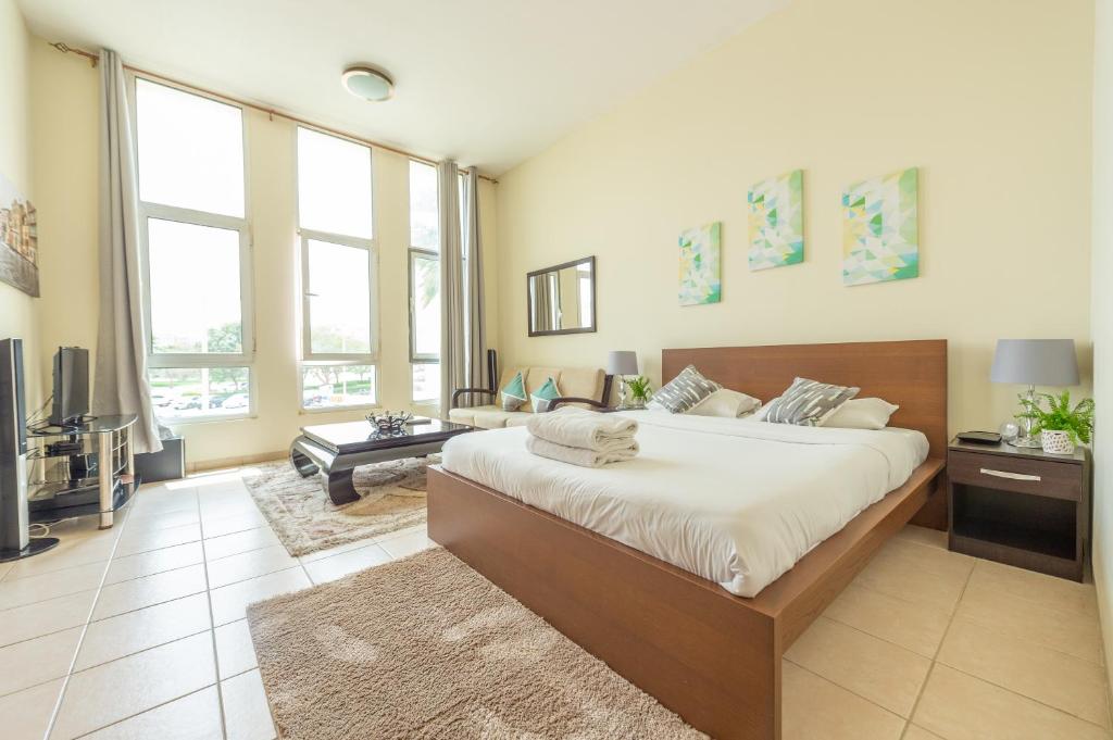 a bedroom with a large bed and a living room at Budget Studio Apt near Metro Stn - IRN in Dubai
