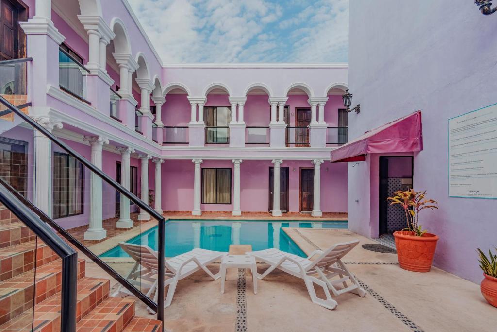 a home with a swimming pool and a pink house at Hotel Lavanda CAS Merida in Mérida