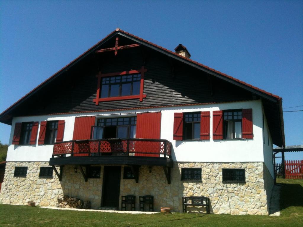 uma casa com janelas vermelhas e brancas e uma varanda em Casa Konigstein em Fundata