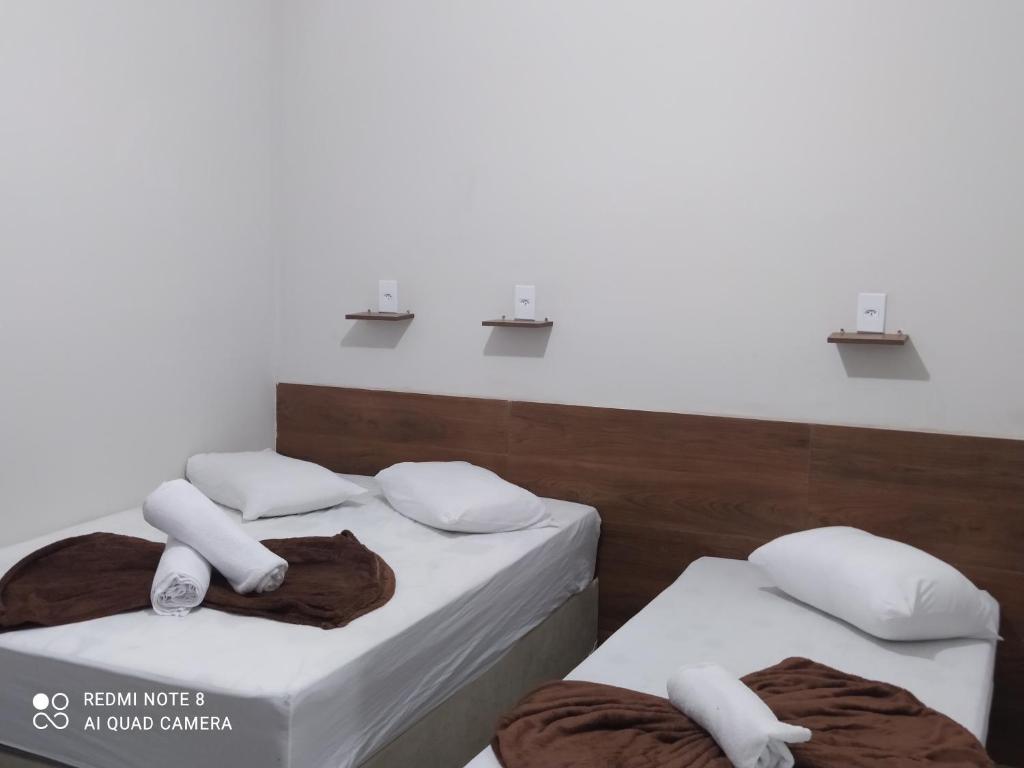 2 aparte bedden in een kamer met witte muren bij Pousada Quarto com ventilador,ar frigobar e garagem in Aparecida