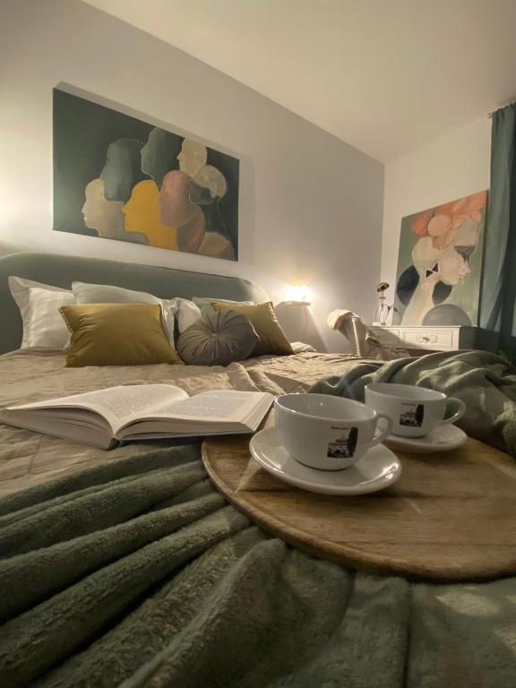 a bed with two cups and a book on it at Boosko Me in Busko-Zdrój