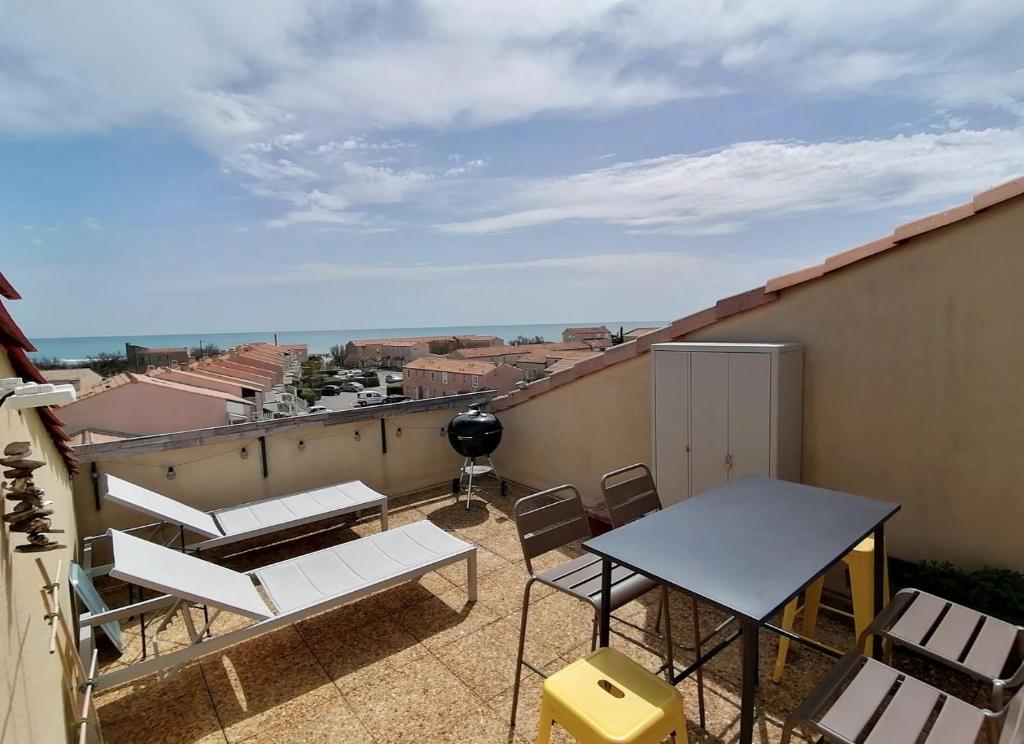 een balkon met een tafel en stoelen op een dak bij Duplex terrasse vue mer accès plage et piscine... in Frontignan